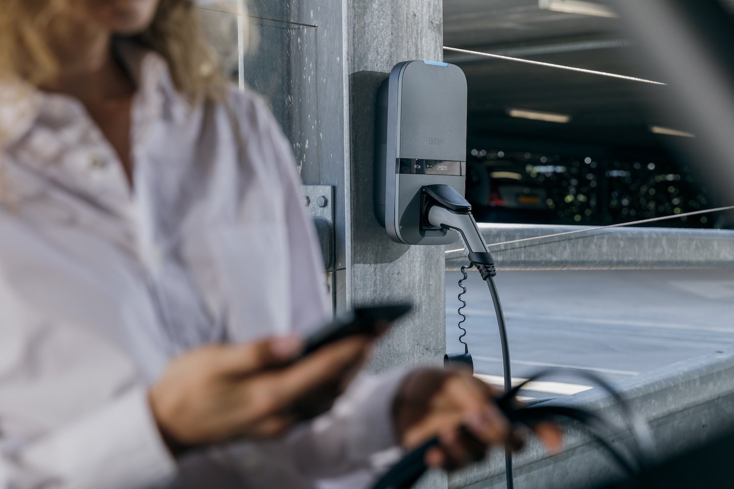 Peblar socket in car park, with person using app